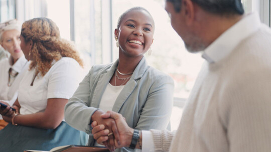 a smiling woman and a man shaking hands